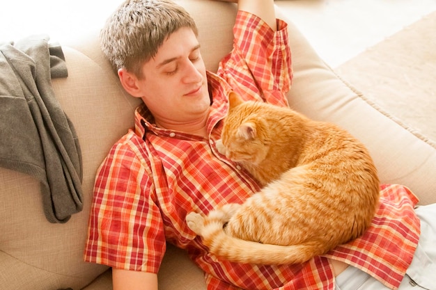 Man liggend op de bank en en op zijn buik liggend een kat