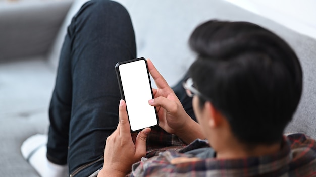 Man liggend op een comfortabele bank en met behulp van slimme telefoon.