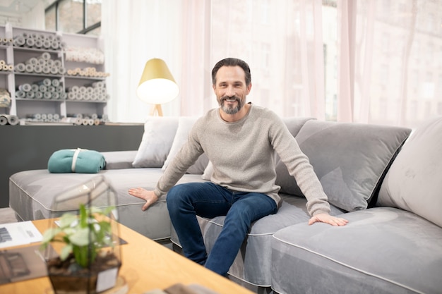 Man in light sweater and jeans feeling good