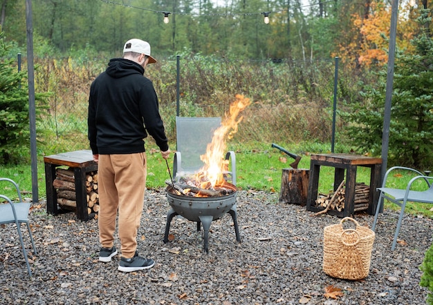 Photo a man lights a barbecue in nature