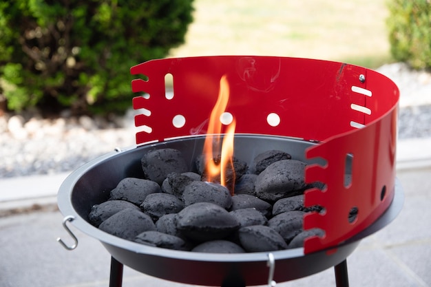 Photo a man lights a fire with a lighter special charcoals for a barbecue