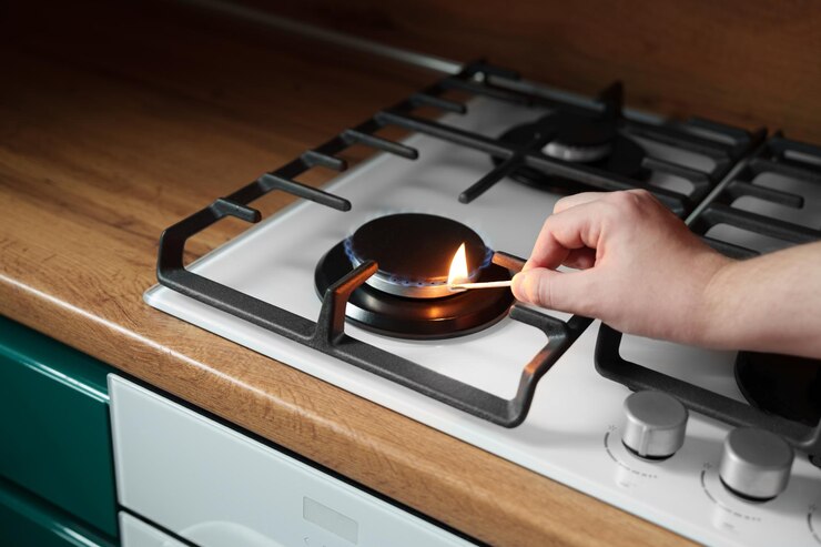 Фотография мужчина зажигает газовую плиту спичкой газ для приготовления пищи - опасность дефицит кухни коричневый столик