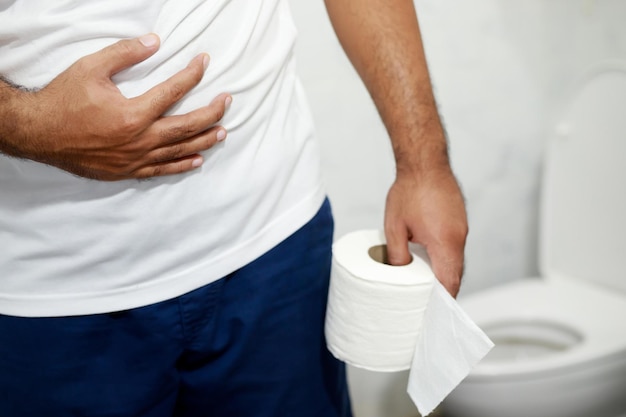 Man lijdt aan diarree hand houden papieren zakdoekje rol voor toiletpot constipatie in badkamer Behandeling maagpijn en hygiëne gezondheidszorg