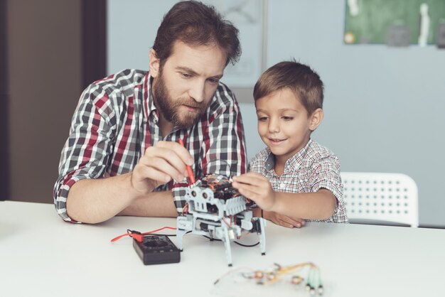 The man and the little boy measure the robot s performance 