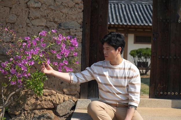 사진 집 앞 의 계단 에 앉아 있는 사람 이 꽃 을 보고 있다