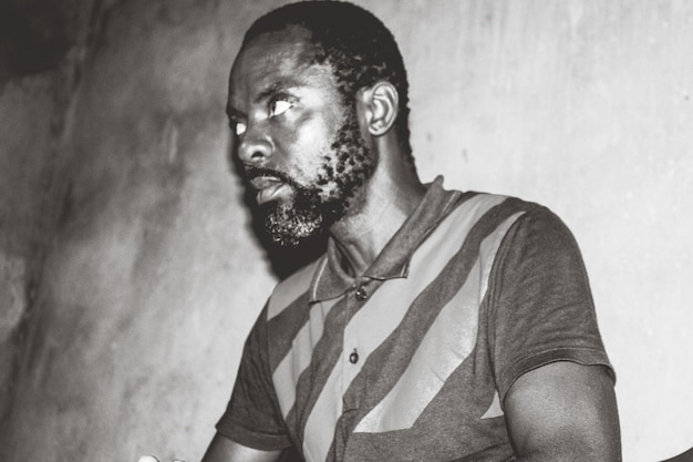 man looking away while standing against wall