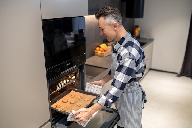 Man looking at baking sheet loading into oven