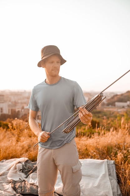 A man looking busy while putting the tent on the hill