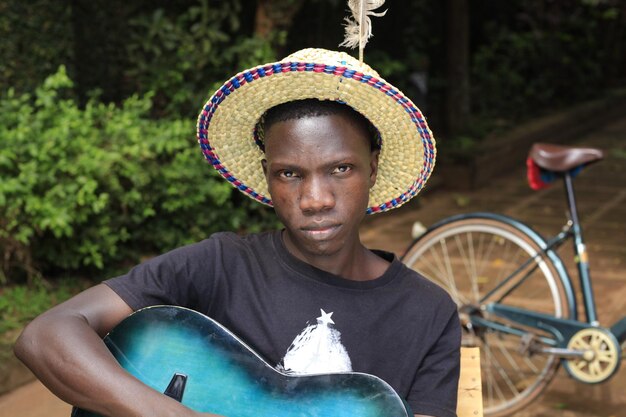 Foto uomo che guarda la telecamera con la chitarra in mano