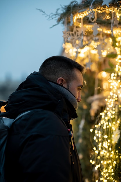 Foto uomo che guarda le luci di natale in un concetto di mercato di natale mercatini e feste di natale