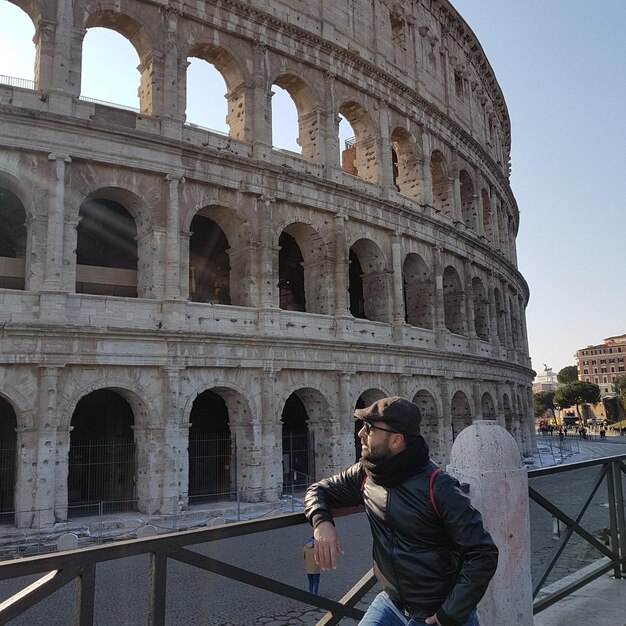 Photo man looking at coliseum in city