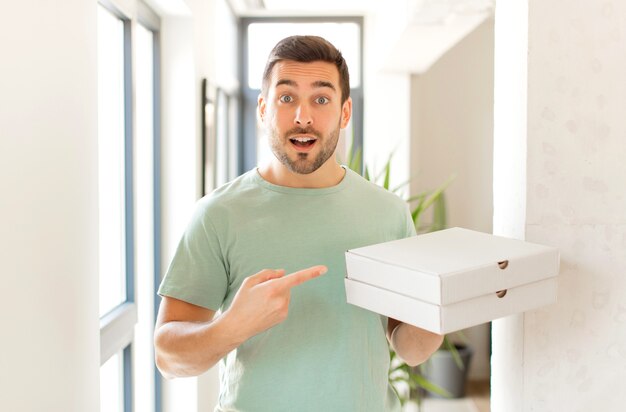 man looking excited and surprised pointing to the side and upwards to copy space