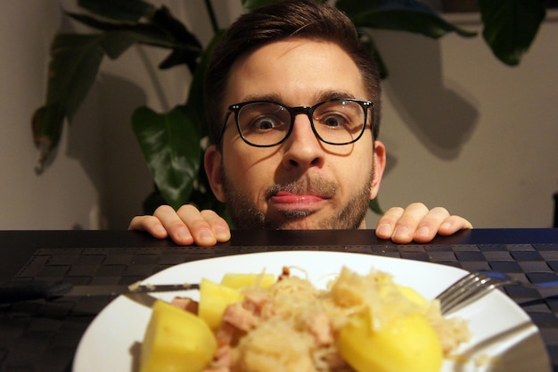 Foto uomo che guarda il cibo nel piatto sul tavolo