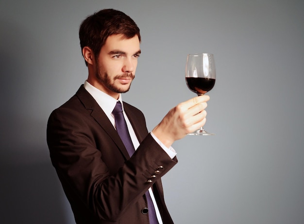 Man looking at the glass of red wine on blue background