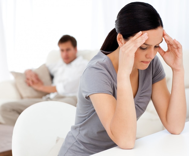 Man looking at his girlfriend having a headache sitting at a table