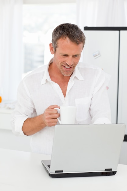 Man looking at his laptop while he is drinking 
