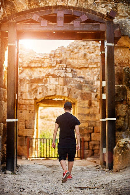 Man looking on Historic ancient temple. Rear shot of a tourist visiting the castle, wearing a casual outfit, he is walking in the lobby