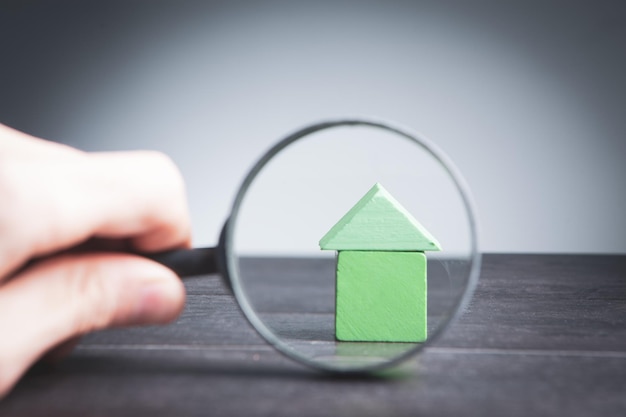 Uomo che guarda la casa con una lente d'ingrandimento