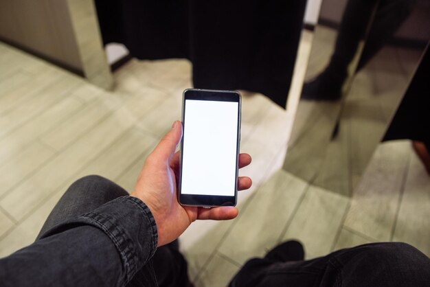 Man looking into phone while his girlfriend do shopping in boutique