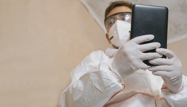 a man looking at a musty white wall Makes notes about cleaning on your phone Specialist of sanitary and epidemiological service