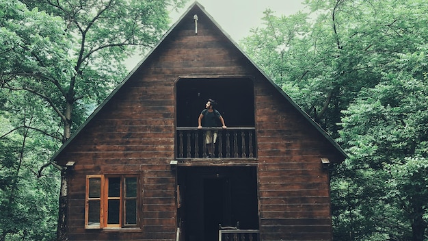 Photo man looking out the balcony of a forest house