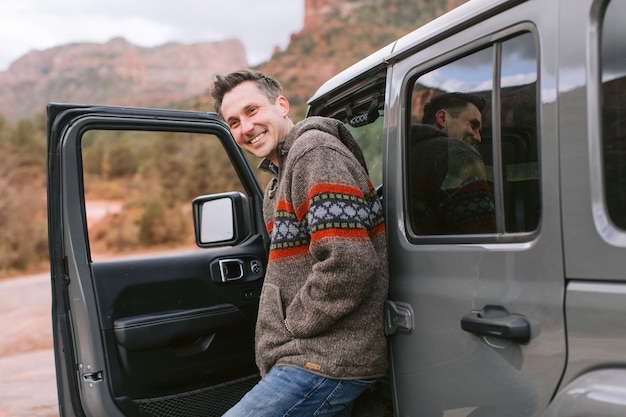 man looking out the open door of his black sports car