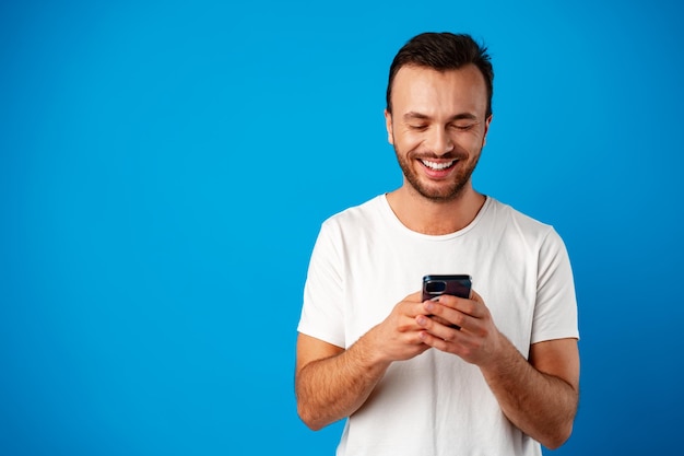 Man looking at phone standing isolated on blue background