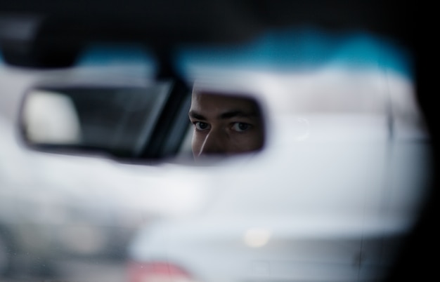 Man looking in the rear view mirror while driving