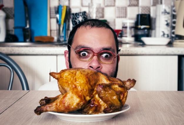 Photo man looking at roasted chicken in kitchen at home