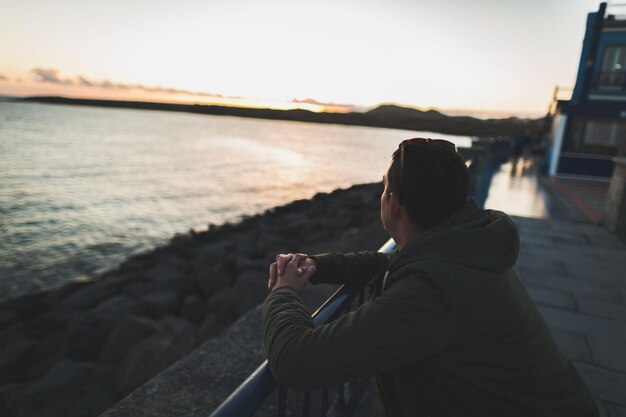 Photo man looking at sea against sky during sunset