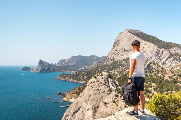 Man looking sea while standing on mountain against clear sky