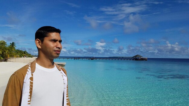 Foto uomo che guarda il mare mentre si trova sulla riva contro il cielo