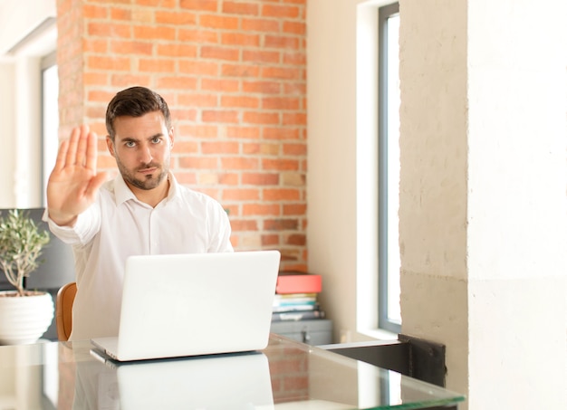 man looking serious, stern, displeased and angry showing open palm making stop gesture