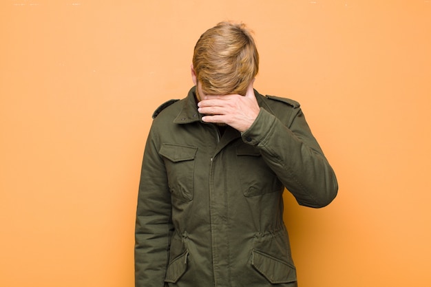 Man looking stressed, ashamed or upset, with a headache, covering face with hand