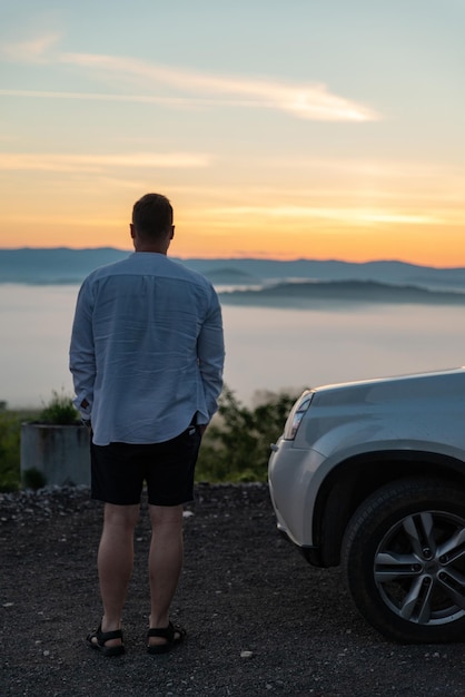 近くの山 suv 車で日の出を見ている男