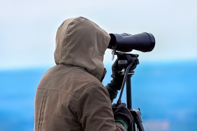 Man looking through binoculars in nature