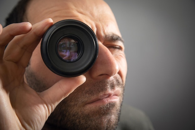 Foto uomo che guarda attraverso l'obiettivo della fotocamera