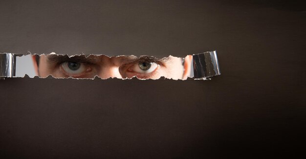 Man looking through hole in paper