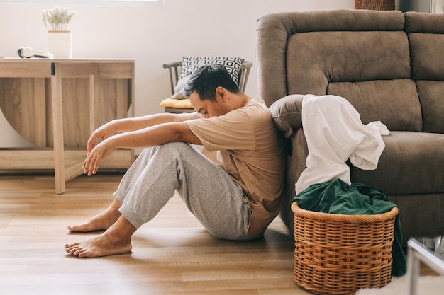 家で汚れた洗濯物を拾いながら、うつ病の問題に疲れて退屈しているように見える男性