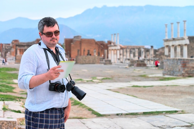 Man looking at touristic map at ruins of ancient city Pompeii, Italy