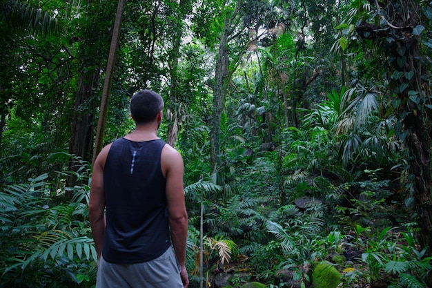 Foto uomo che guarda il giardino verde tropicale