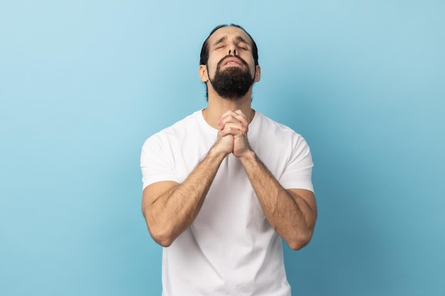 Man looking up holding hands together praying God asking for health and support pleading for healing