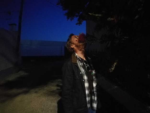 夜木のそばに立っている男性が目を上げています