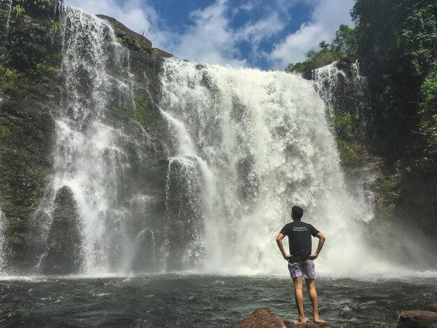 Foto uomo che guarda la cascata