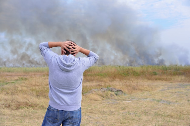 A man looks at a burning field