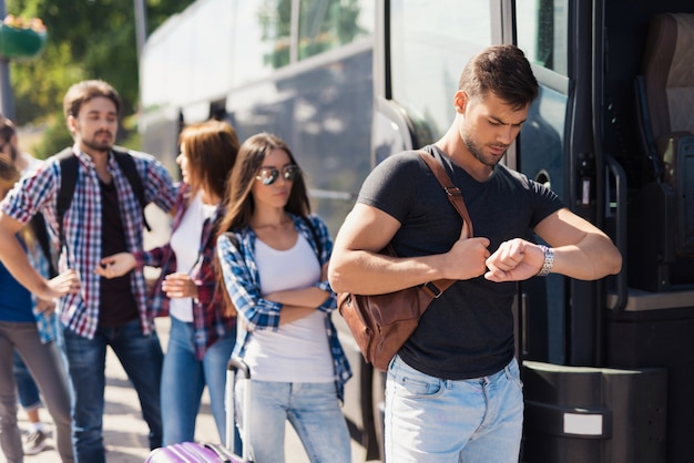 Man looks at his watch and gets on the bus.