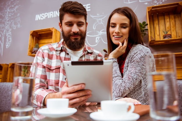 A man looks at a tablet in a cafe.