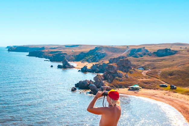 A man looks through binoculars at the seascape Rocky coast of the Sea of Azov General's beaches Travel and tourism