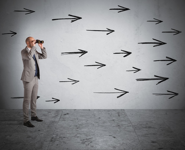 Man looks through binoculars with arrows on the wall