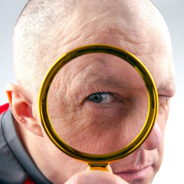 Photo man looks through a magnifying glass